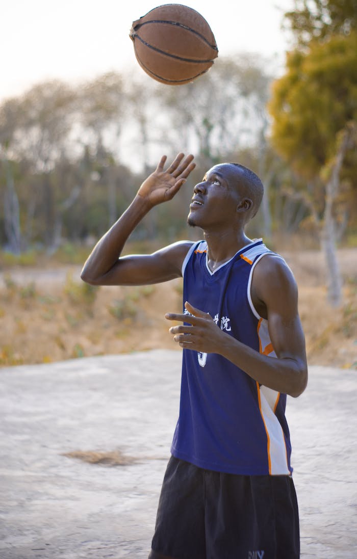 A man in a tank top playing basketball outside in Lafia, Nigeria.